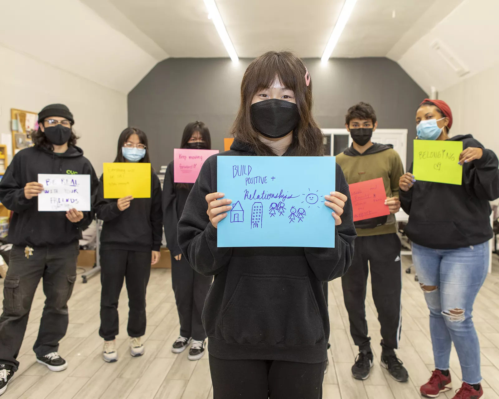Teens holding up written signs with positive messages for mental health