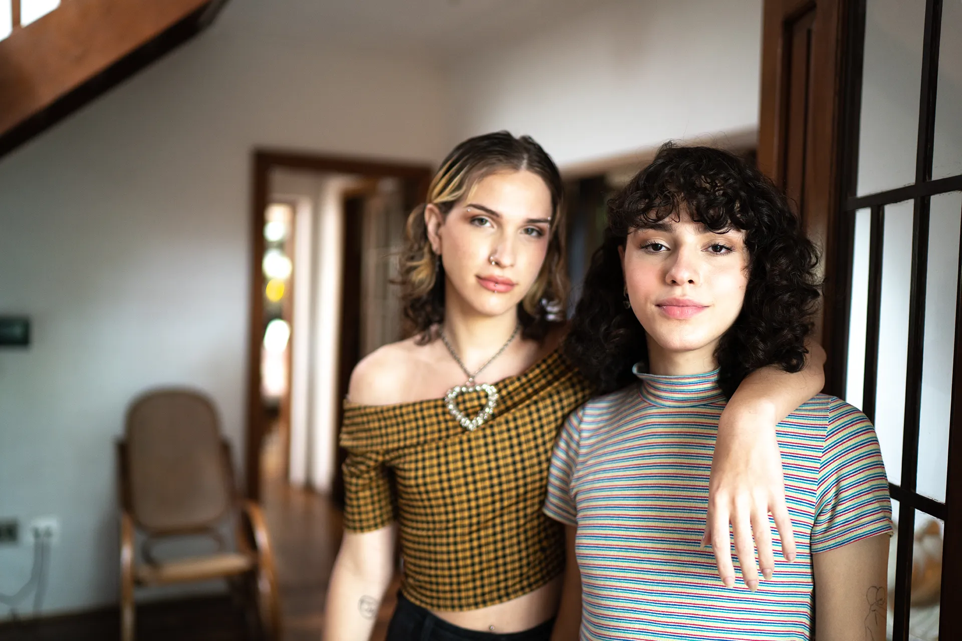 Two young woman posing with ones arm around the other