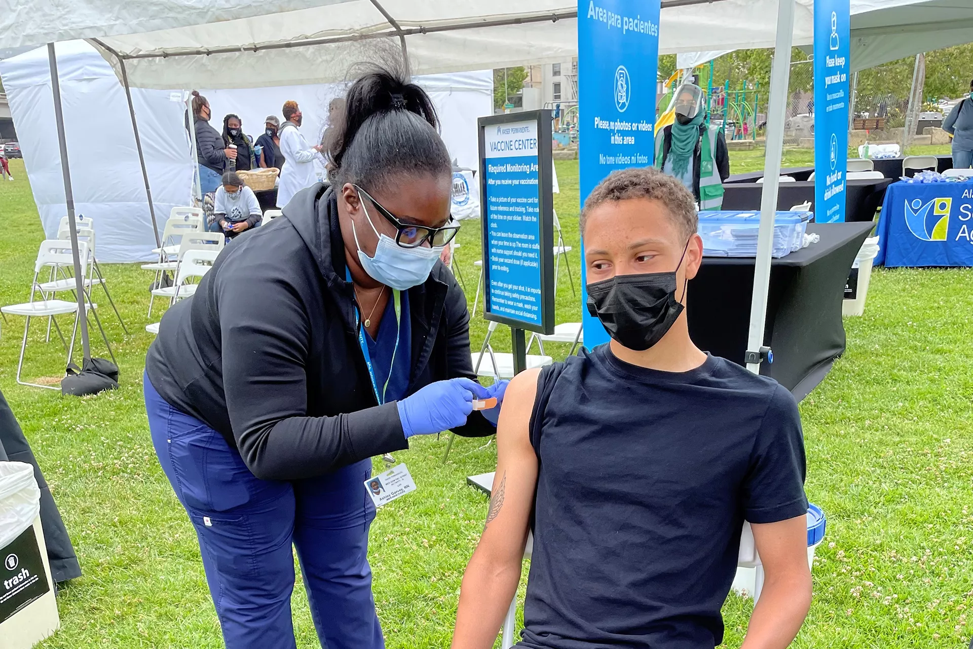 Teen getting vaccinated by nurse at outdoor clinic