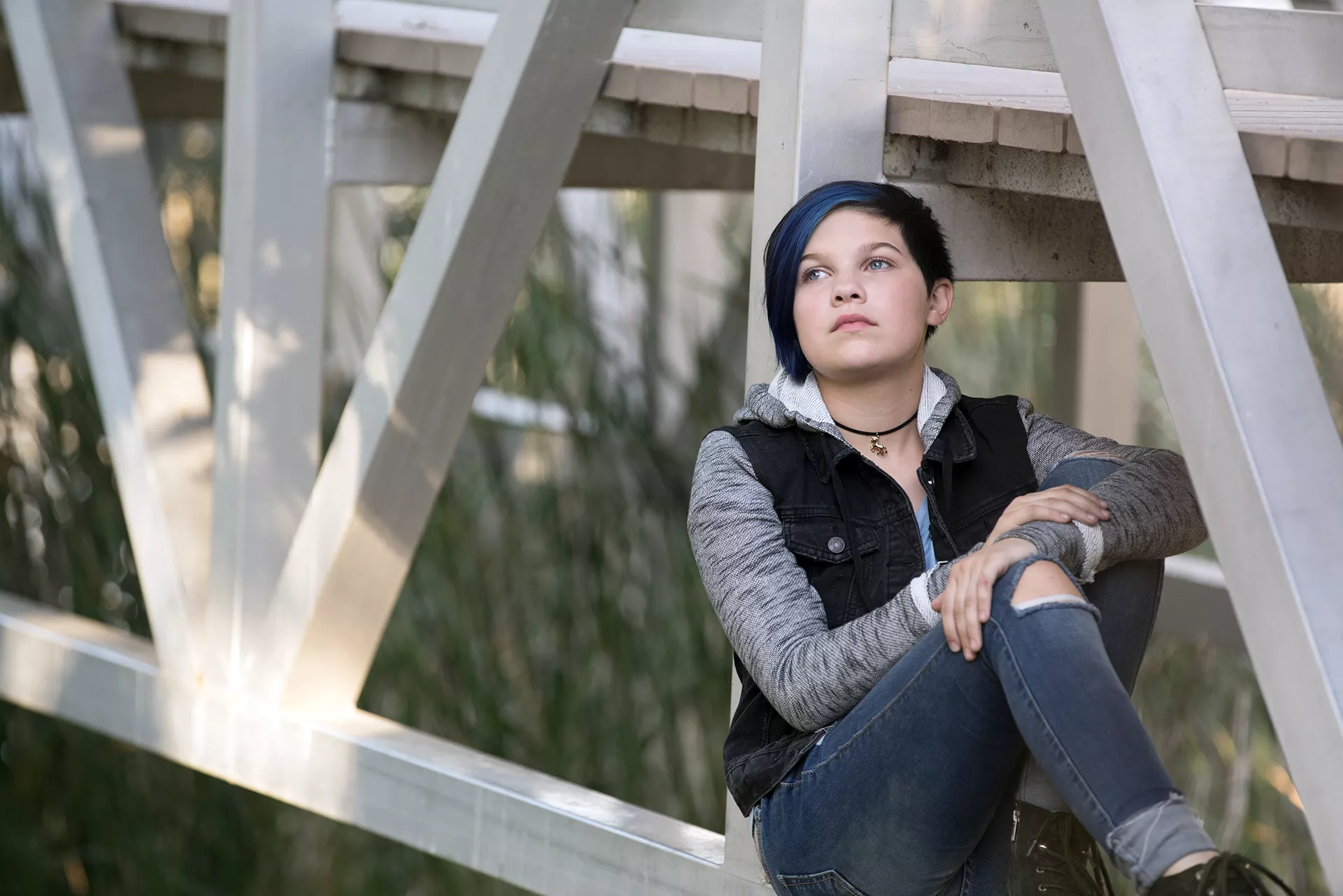 Teen sitting on walking bridge looking melancholy