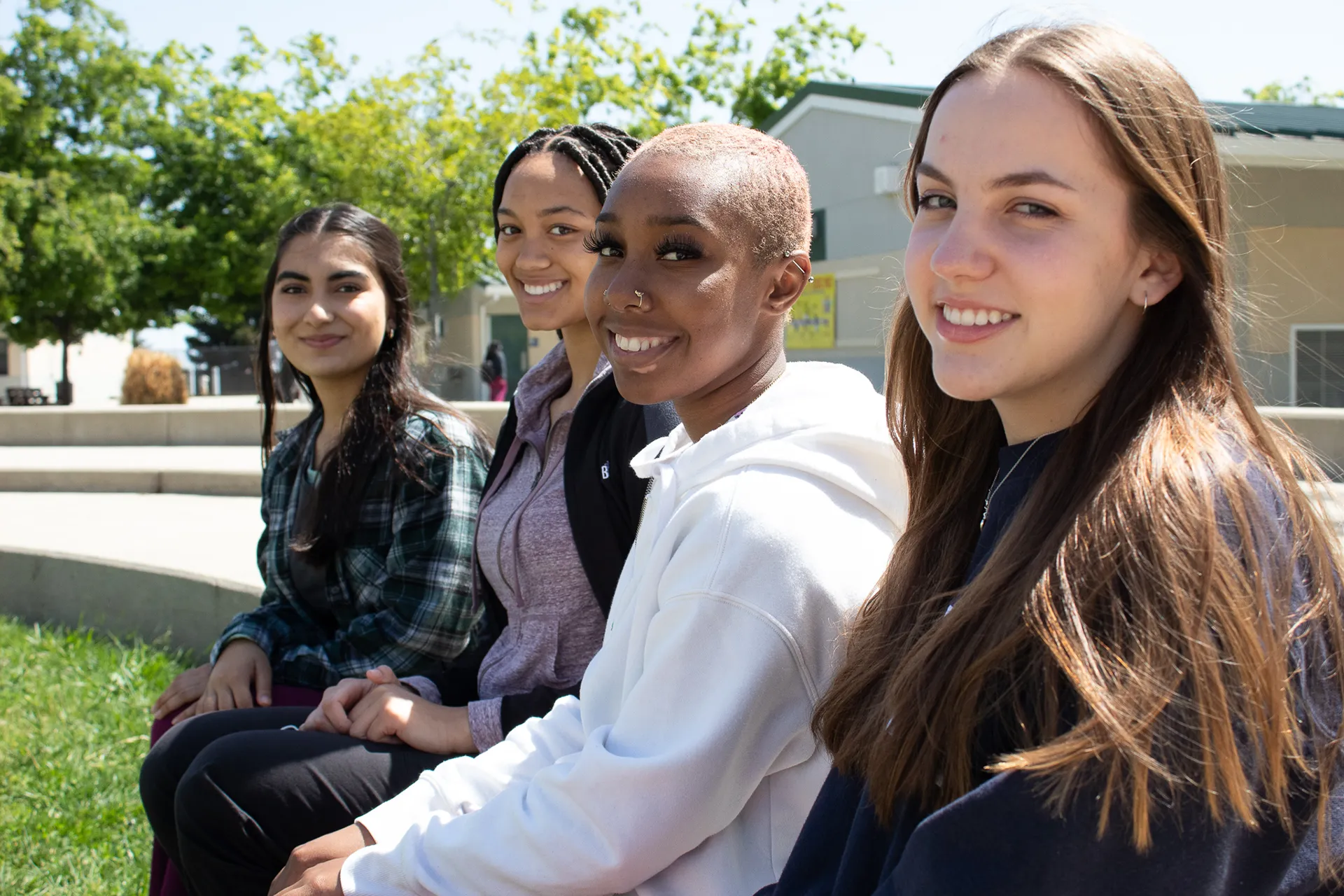 Four female mental health students sitting outside smiling
